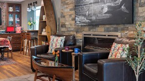 Un salon avec une cheminée, des canapés en cuir, une table basse et une bibliothèque.