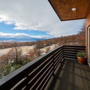 Une terrasse en bois offrant une vue sur une montagne enneigée et les couleurs automnales des arbres.