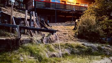 A rustic wooden cabin with a balcony, surrounded by natural landscape and trees.