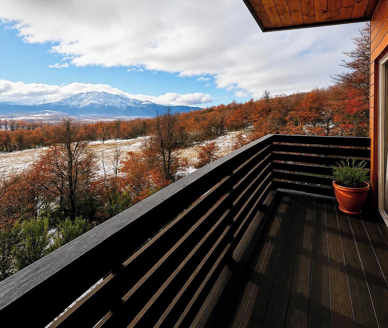A balcony with a view of a snowy mountain and autumn trees.