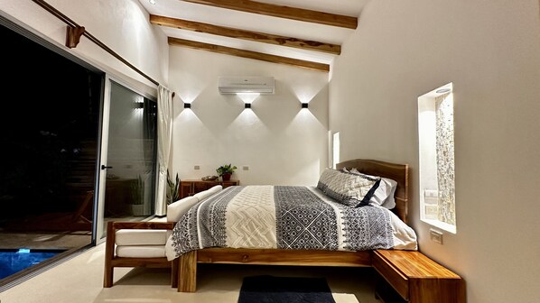Un dormitorio con cama, mesita de noche, ventana y equipo de aire acondicionado.