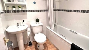 A bathroom with a sink, toilet, and bathtub. - BAMBU (London)