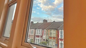 A window with a view of terraced houses and a clear sky. - BAMBU (London)