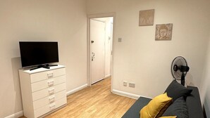 A modern living room with a sofa, a TV, and a white dresser. - BAMBU (London)