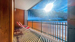 A balcony with a view of a snowy landscape and a sun shining through the window.