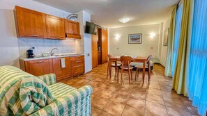 A compact living space with a kitchenette, dining area, and a sofa.