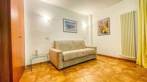 A living room with a sofa, a glass table, and two wall-mounted pictures.