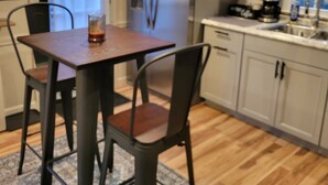 Une cuisine équipée d’une table à manger, de chaises, d’un réfrigérateur, de placards et d’une machine à café.