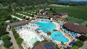 An aerial view of a resort with multiple swimming pools, sun loungers, and a large building with a roof. - Mobilehome with terrace, air conditioning and pool (Fondotoce di Verbania)
