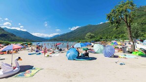 Una playa con flotadores de cisne e pato inflables, sombrillas y gente relajándose.