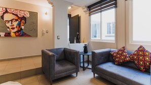 A modern living room with a sofa, armchairs, a coffee table, and a painting on the wall.
