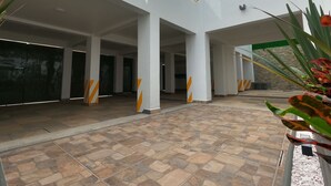 A spacious indoor area with a tiled floor, white walls, and large pillars.