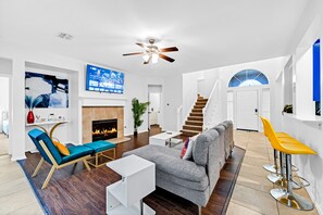 Ein geräumiges Wohnzimmer mit Kamin, einer Couch, einem Fernseher und einer Treppe.