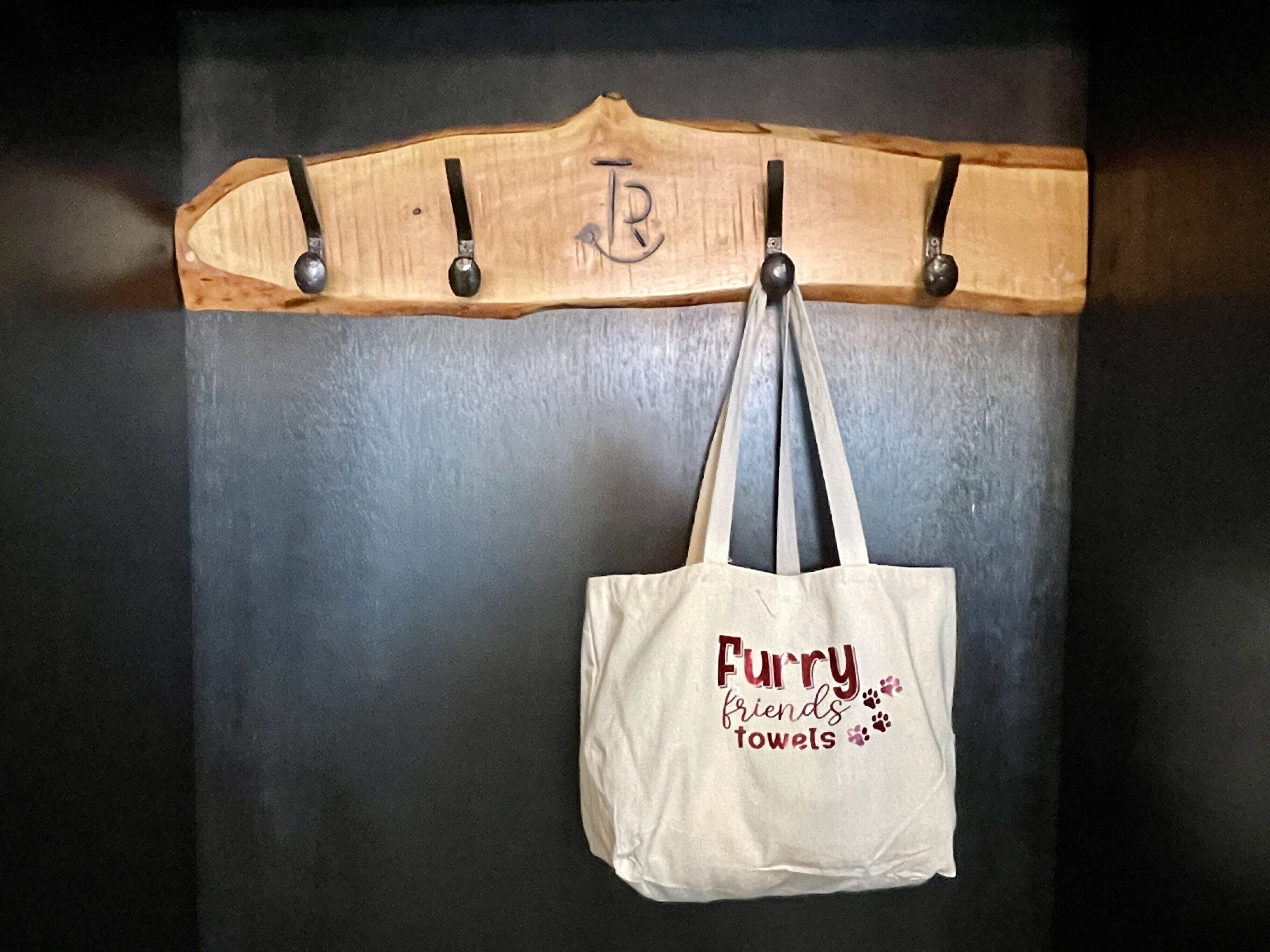 Un porte-manteau en bois doté de quatre crochets, avec un sac fourre-tout blanc suspendu à l’un de ces crochets.