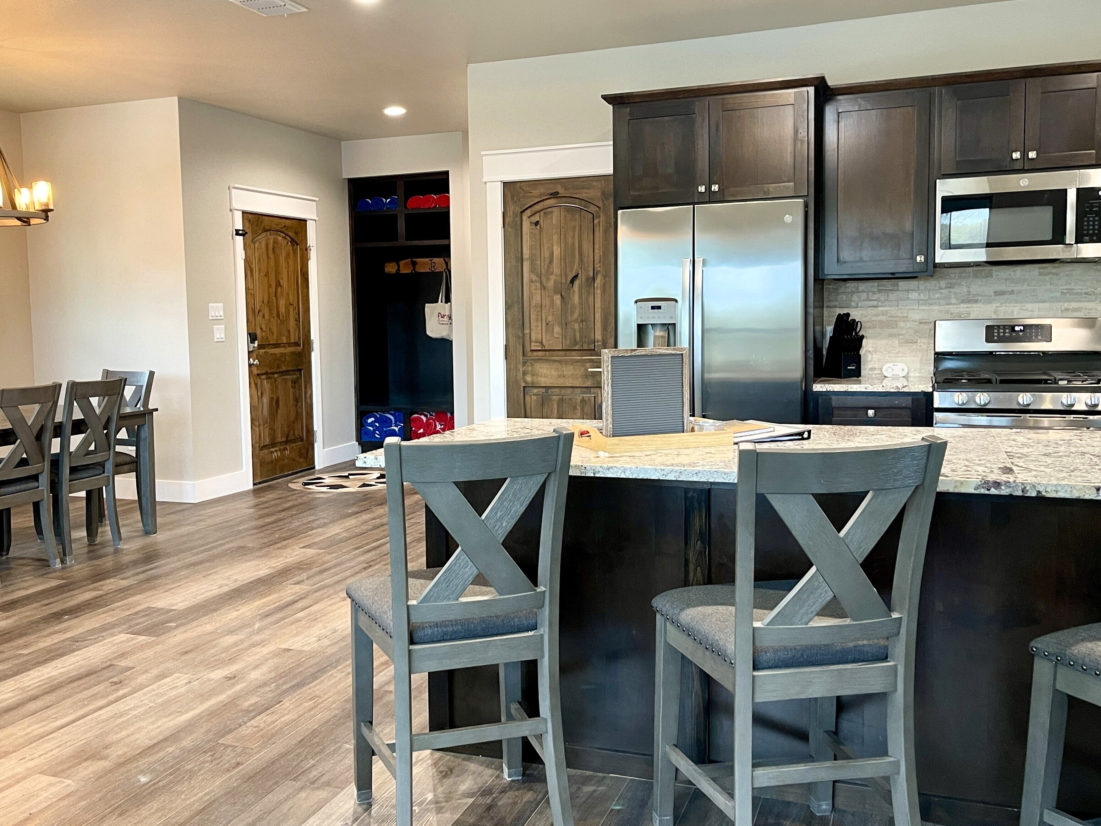 A modern kitchen with dark wood cabinets, stainless steel appliances, and a marble countertop.