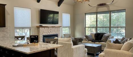 A spacious living room with a fireplace, comfortable seating, and large windows.