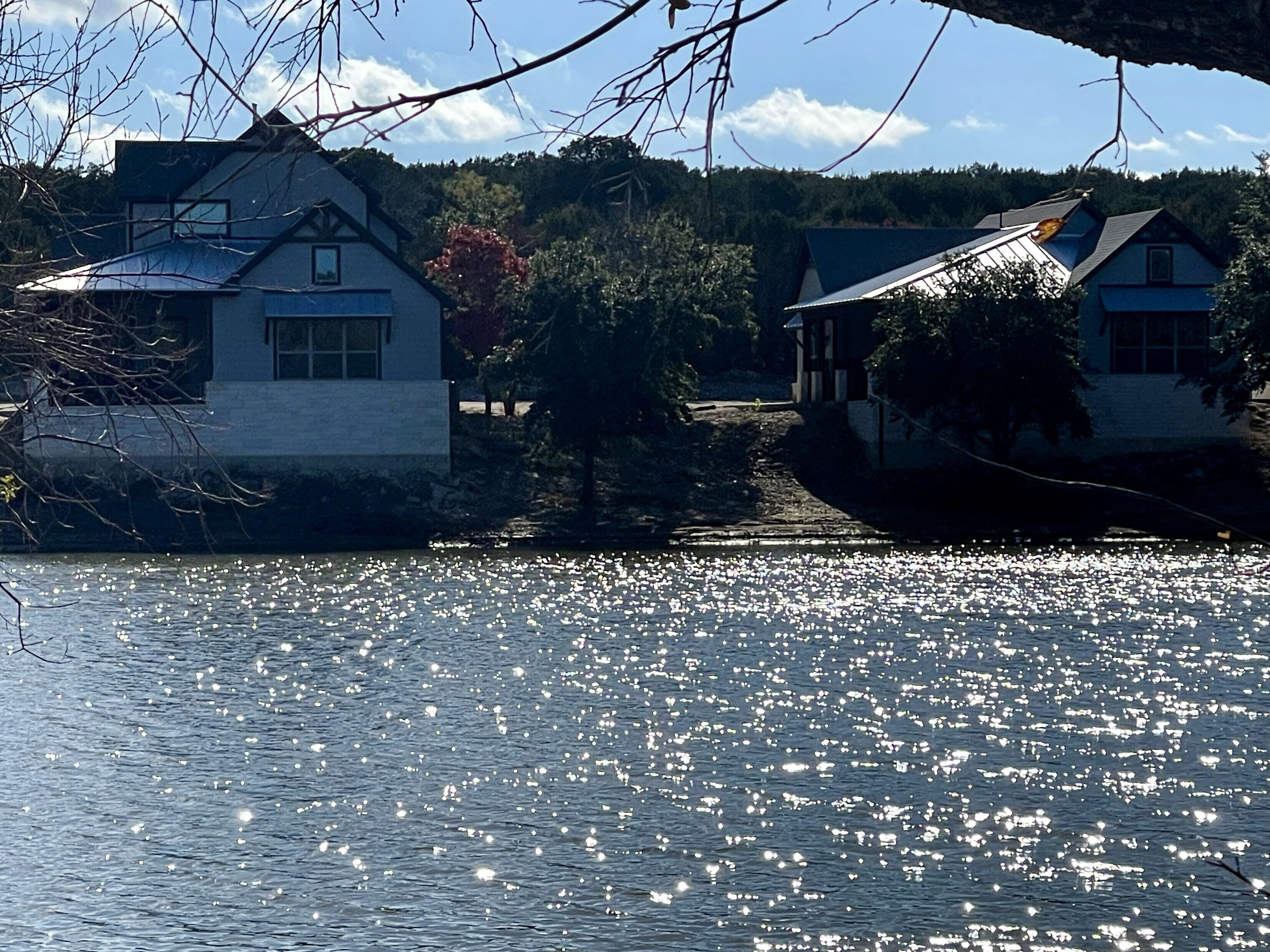 A house by a lake with a clear view of the water and surrounding trees.