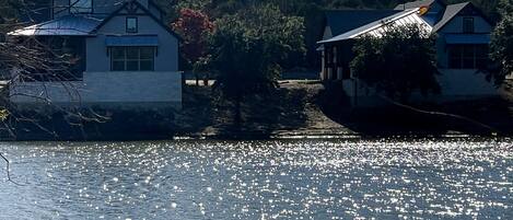A house by a lake with a clear view of the water and surrounding trees.