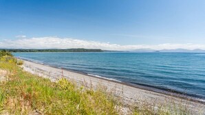 A beach with a clear view of the sea and distant mountains. - Absolute Lake Front - 5 Mile Bay. Lakes edge with uninterrupted views,  kayak for you to use. (Taupo)