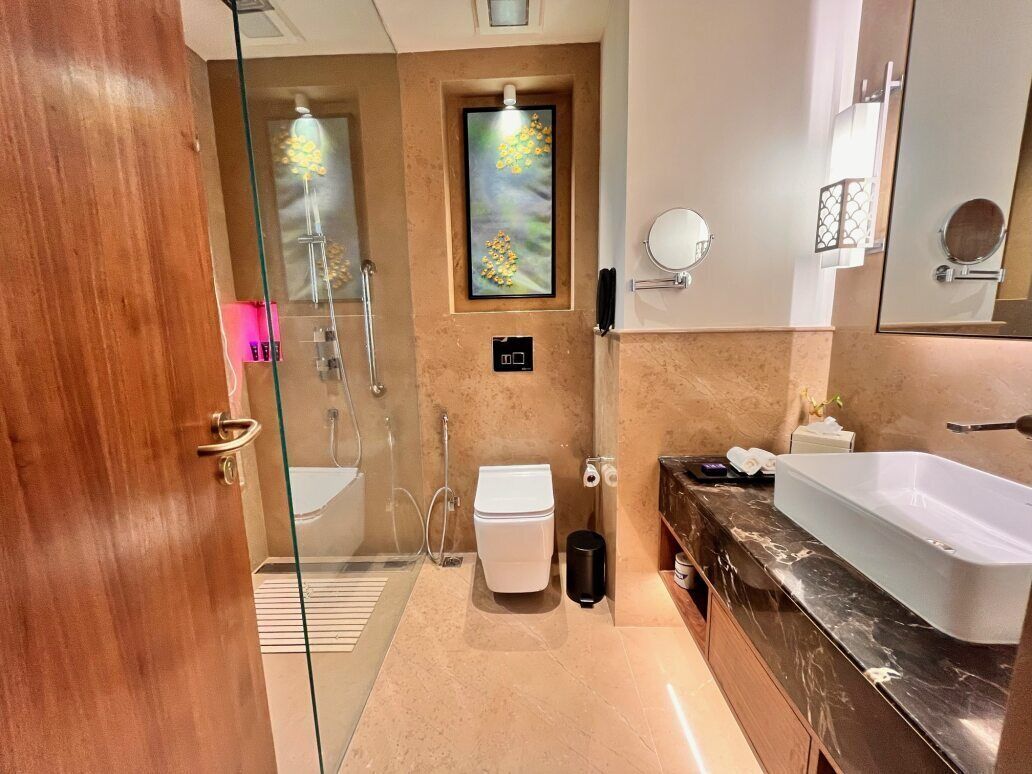 Un baño moderno con cabina de ducha de vidrio, inodoro blanco, lavamanos grande y encimera de mármol.