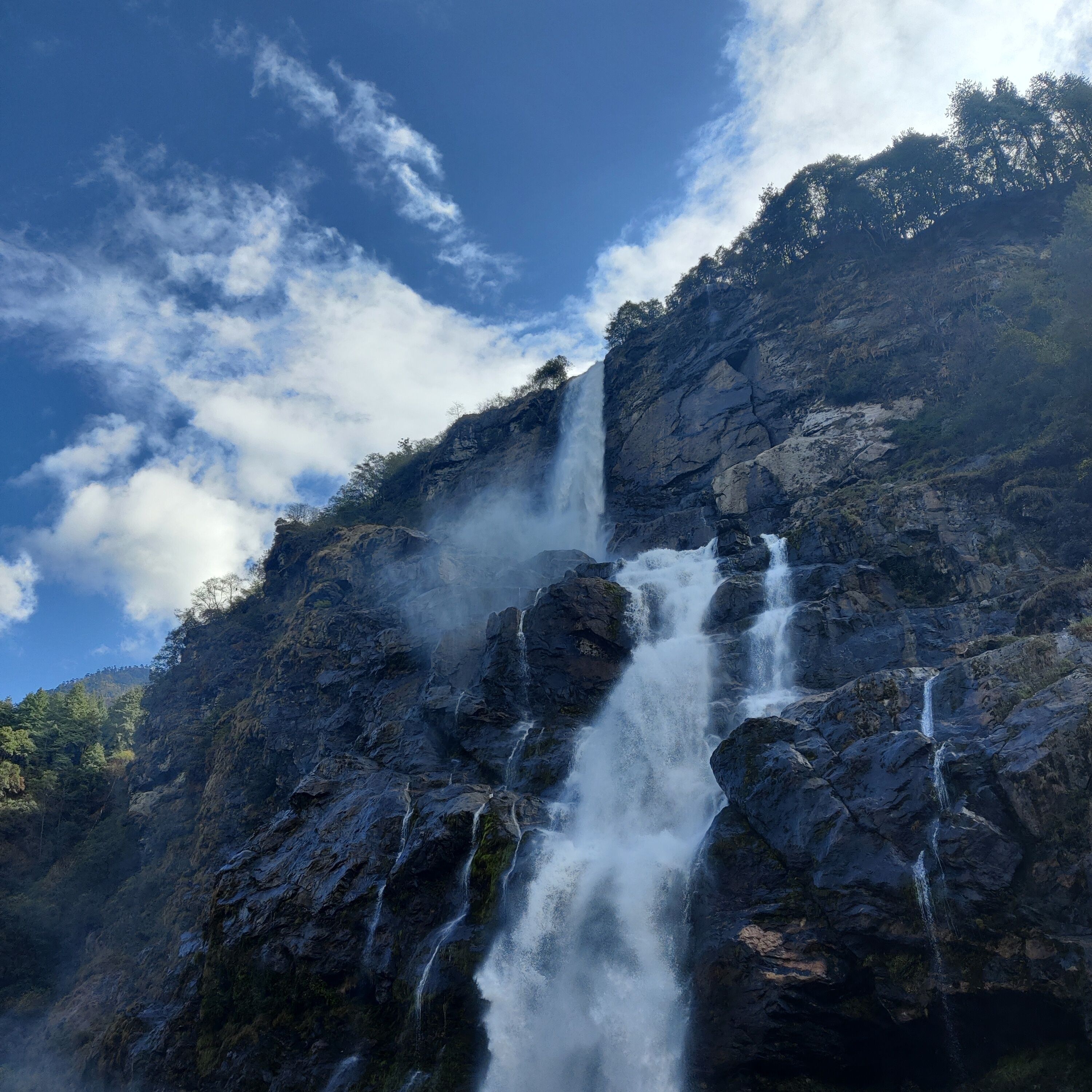 A waterfall cascading down a rocky cliff surrounded by dense forest.