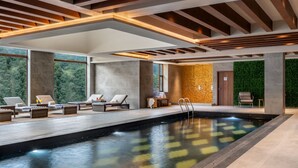 A modern indoor swimming pool with lounge areas, large windows, and a green wall. - Vivanta Tawang (Tawang)