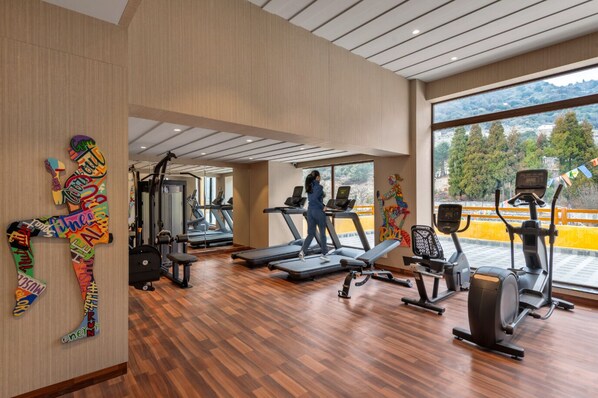 A gym with treadmills, exercise bikes, and a wooden floor.