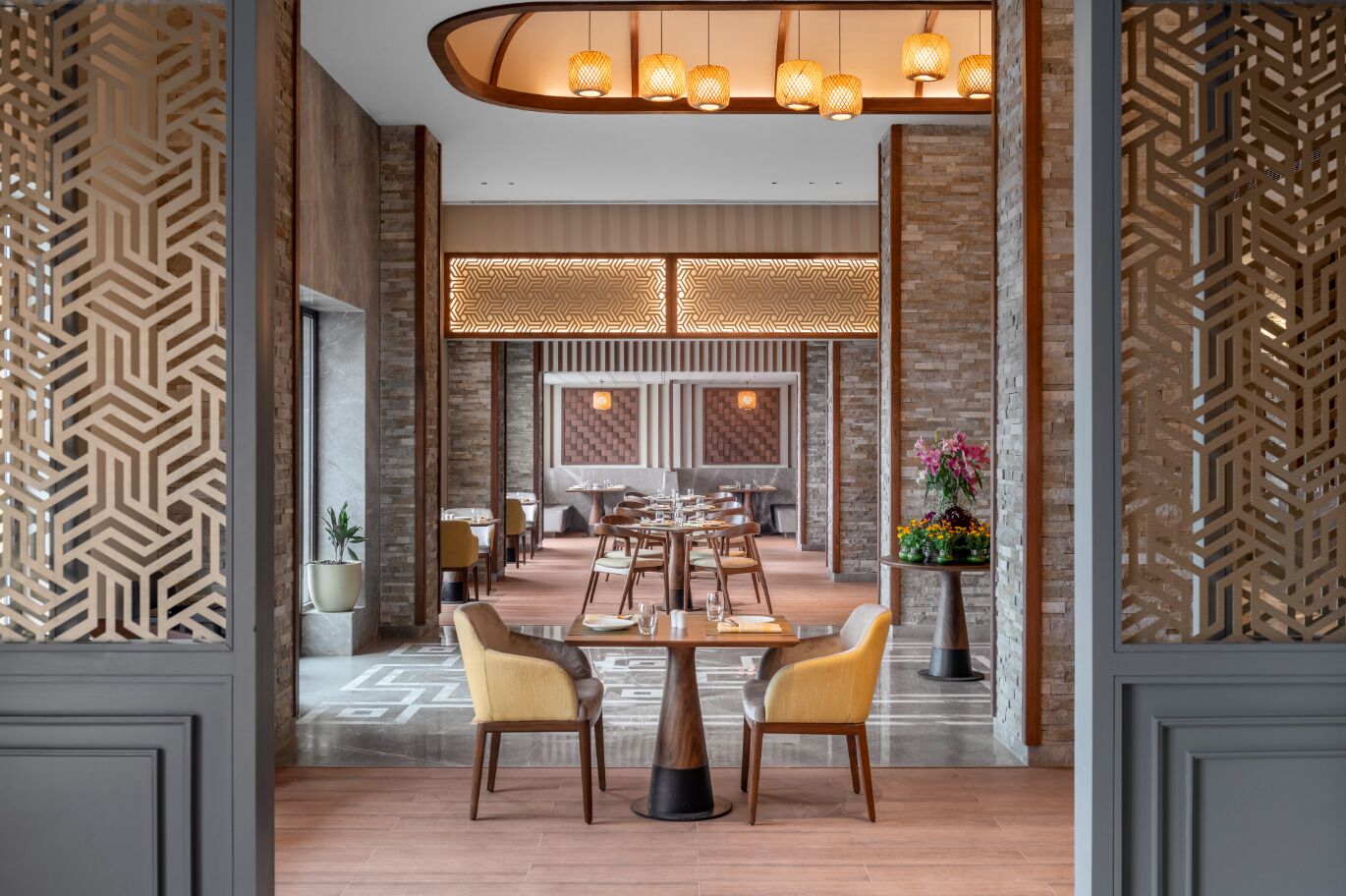 A modern dining area with a central table, chairs, and decorative lighting.