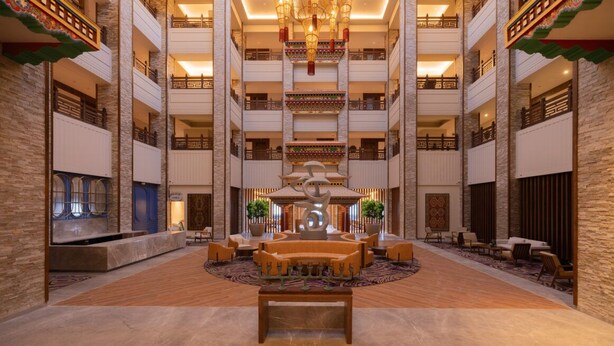 A spacious lobby with a central seating area, multiple floors with balconies, and traditional decor elements. - Vivanta Tawang (Tawang)