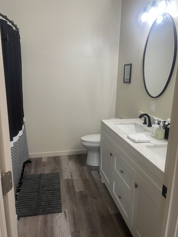 A bathroom with a white toilet, a sink with a mirror above it, and a black and white striped towel hanging on a door. - GameRoom, Jacuzzi, Fenced back,Park, BMX, Skatepark, Pickleball walking distance (Show Low)