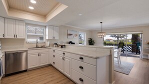Een moderne keuken met witte kasten, een inbouwvaatwasser en een groot eiland.