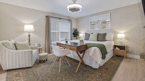 Een moderne slaapkamer met een bed, bureau, stoel en een groot raam met jaloezieën.