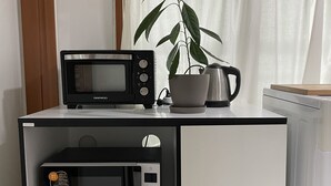 A compact kitchen with a microwave, a coffee maker, and a potted plant.