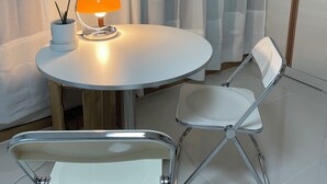 A modern room with a round table, two chairs, a lamp, and a potted plant.