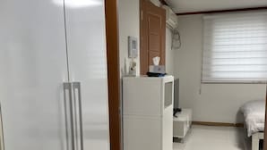 A bedroom with a bed, a wardrobe, a desk, and a window with blinds.