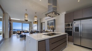 Una cocina moderna con una isla grande, electrodomésticos de acero inoxidable y vistas al exterior.