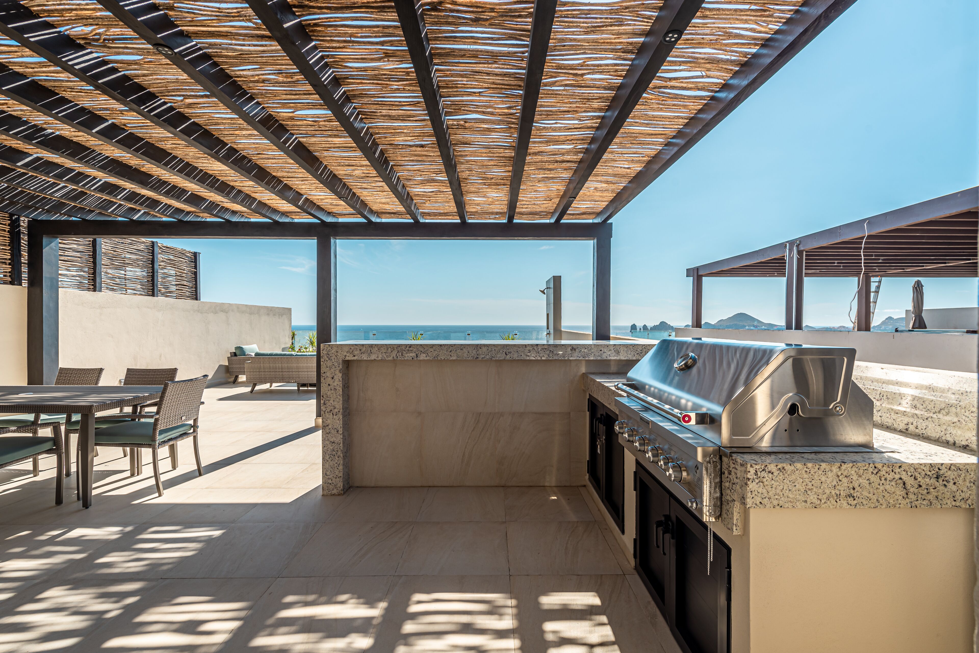 Une cuisine extérieure avec vue sur l’océan, un barbecue et un espace détente.
