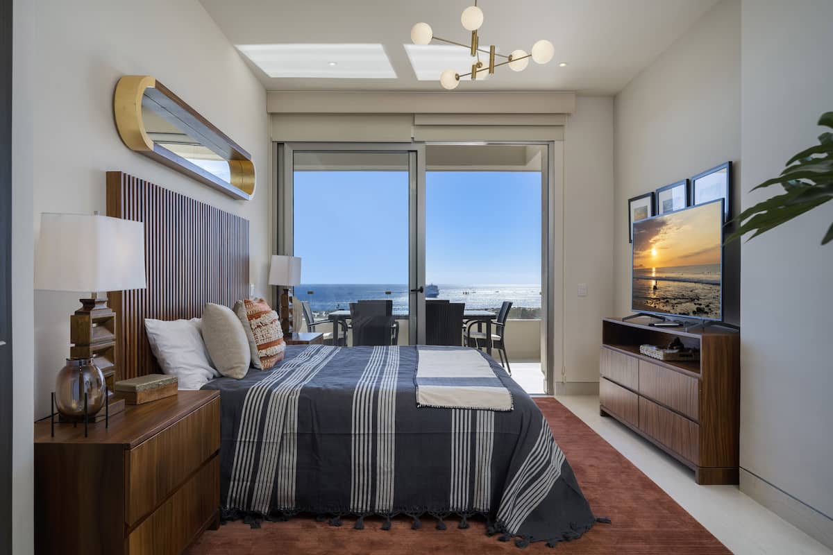 Un dormitorio moderno con una cama grande, un televisor y vista al océano.
