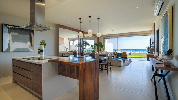 Una cocina moderna con una isla central, ventanas amplias y vista al océano.