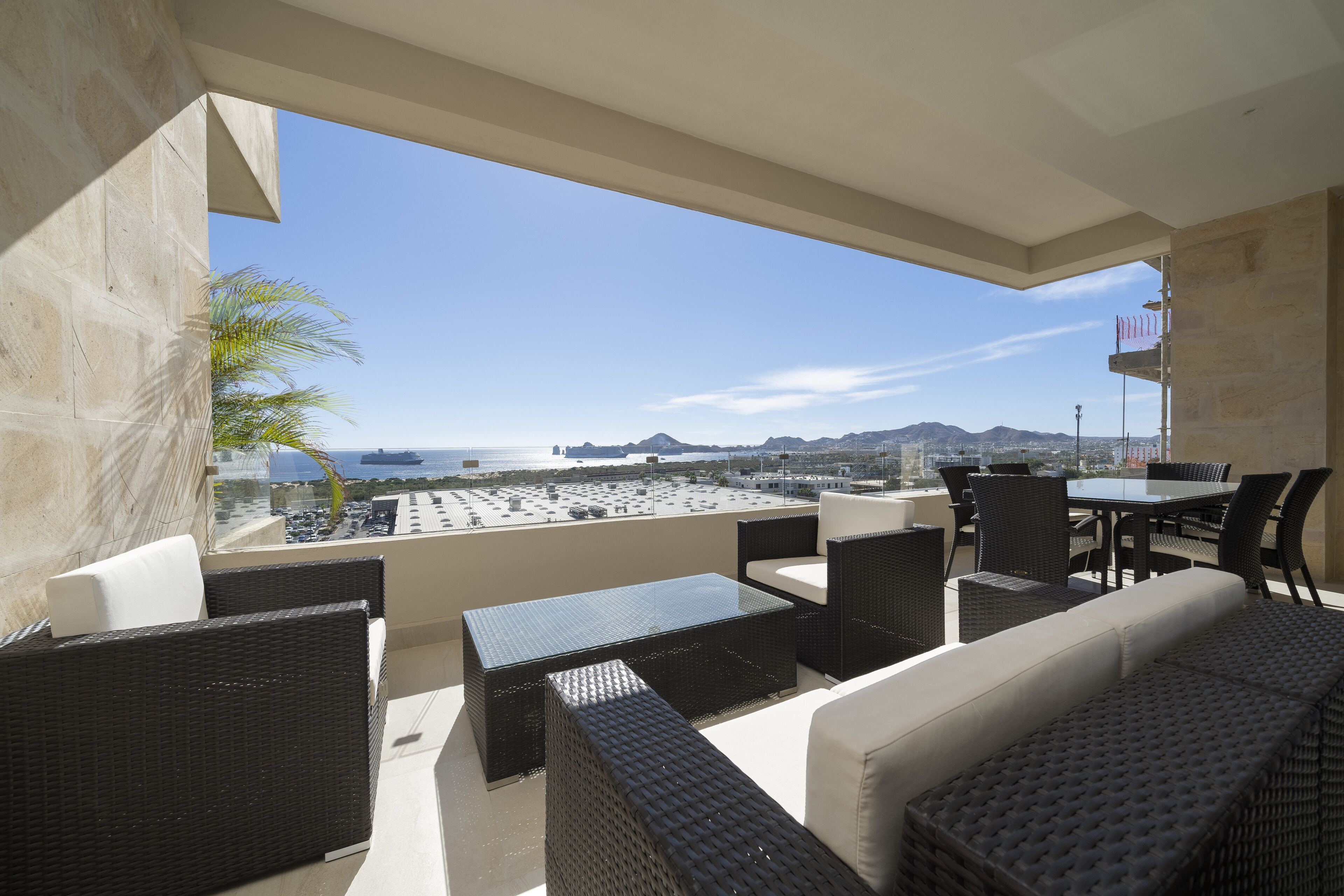 Une terrasse sur le toit, aménagée avec des meubles en osier, une table en verre et offrant une vue sur la ville et l’océan.