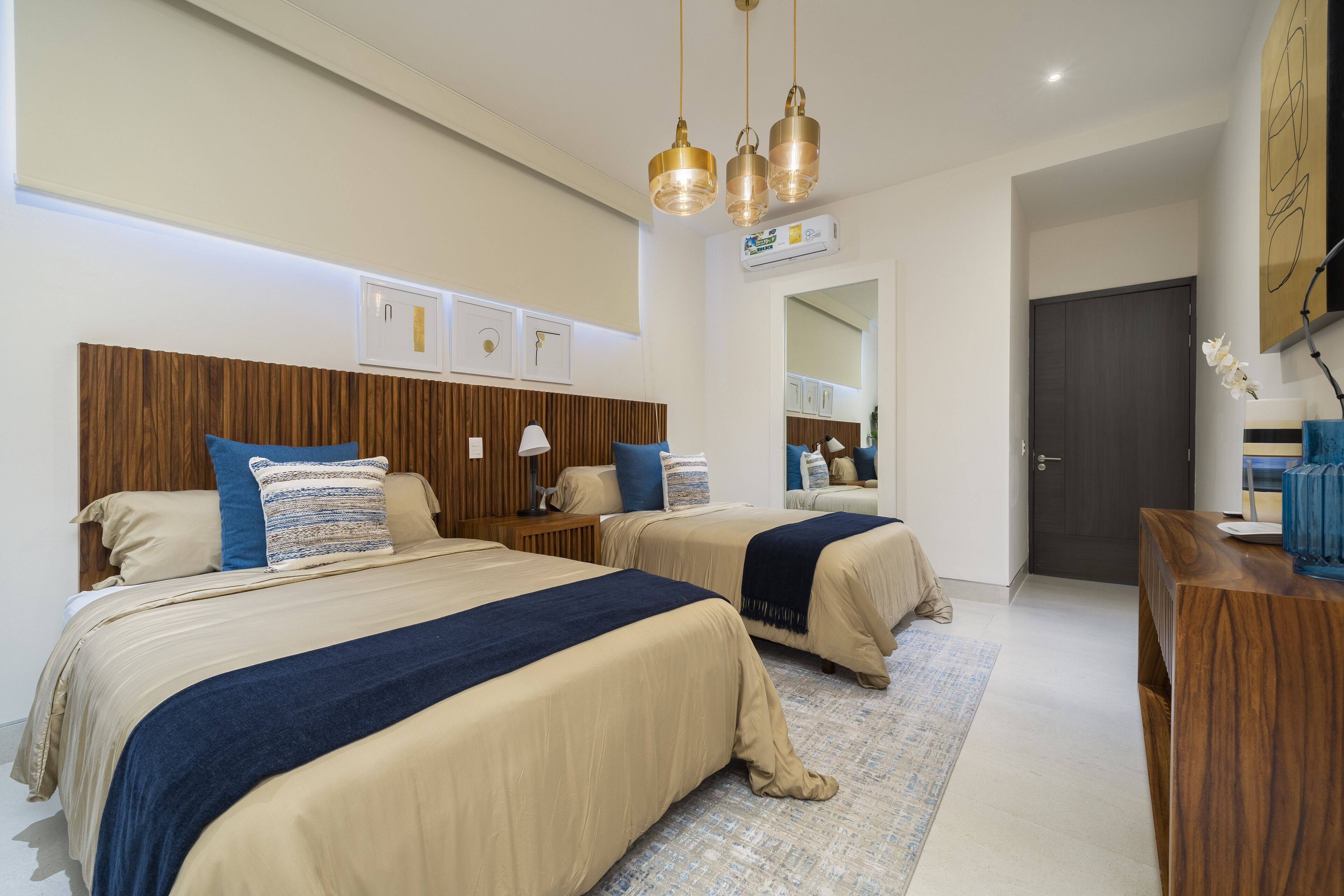 A hotel room with two beds, a wooden headboard, a desk, and a mirror.
