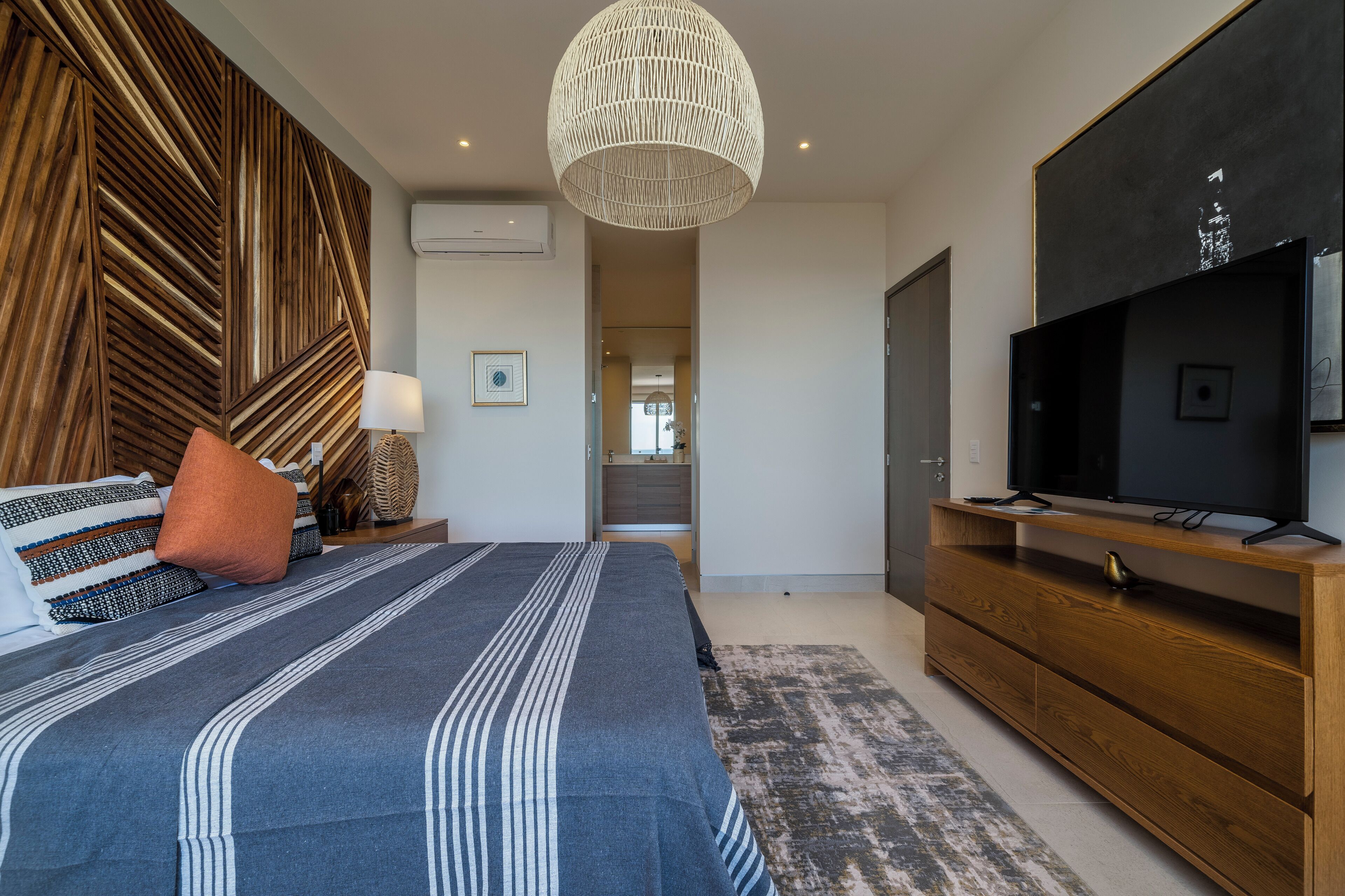 Une chambre moderne avec un grand lit, une télévision, une tête de lit en bois et un décor mural original.