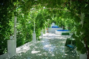 A covered outdoor area with a tiled floor, a pool, and a table with a chair.