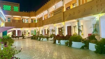 A hotel courtyard with a paved walkway, multiple guest rooms, and potted plants.