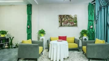 A living room with two grey sofas, a round white table, and green curtains.
