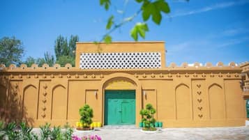 A building with a green door, a white lattice structure above, and a courtyard with plants.