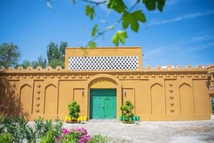 A building with a green door, a white lattice structure above, and a courtyard with plants.