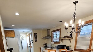 Et rummeligt køkken med spiseplads, træskabe og en lysekrone.