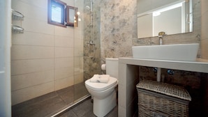 Et badeværelse med bruser, toilet og håndvask.