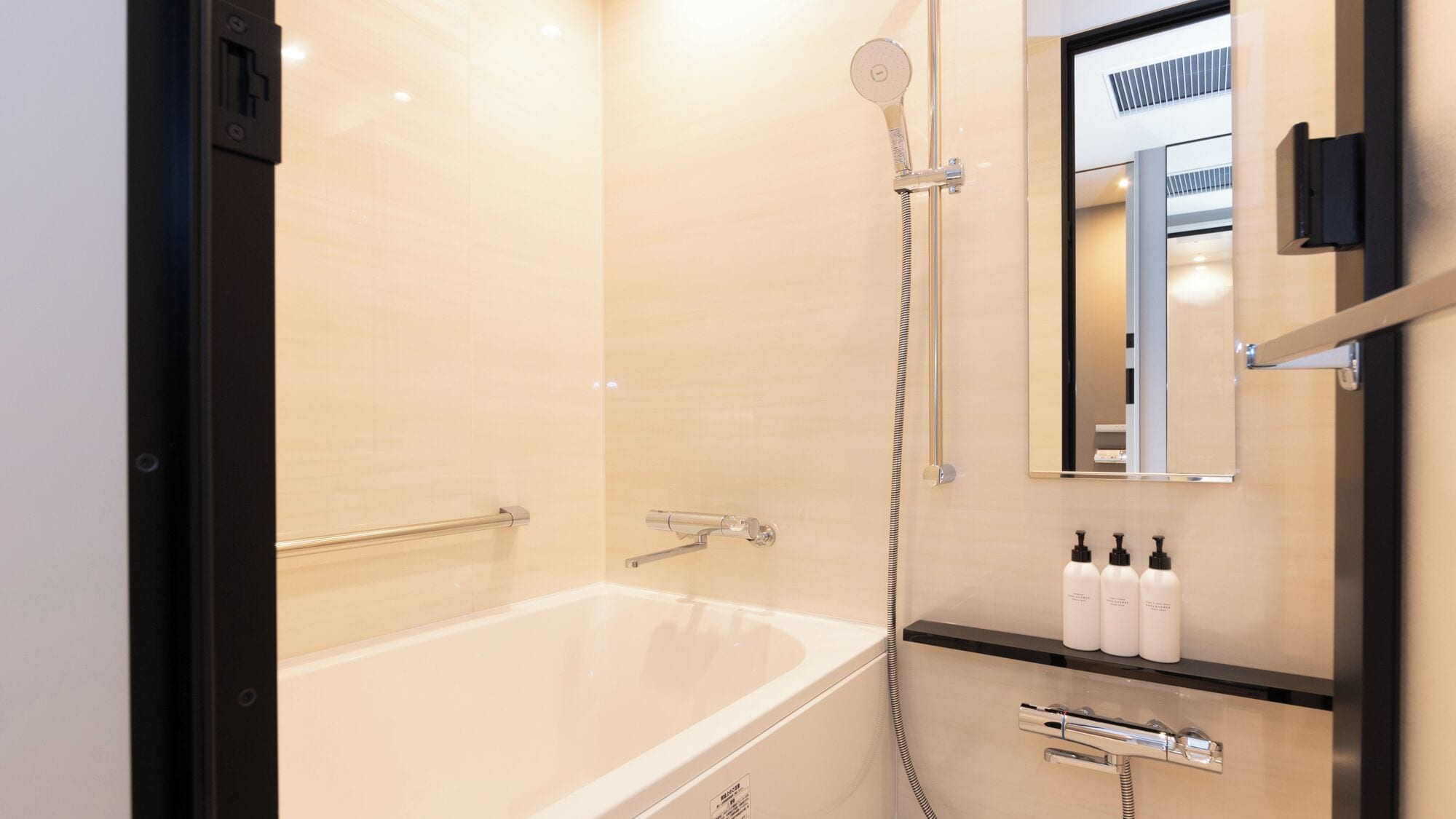A modern bathroom with a bathtub, a handheld showerhead, a towel rack, and a mirror.